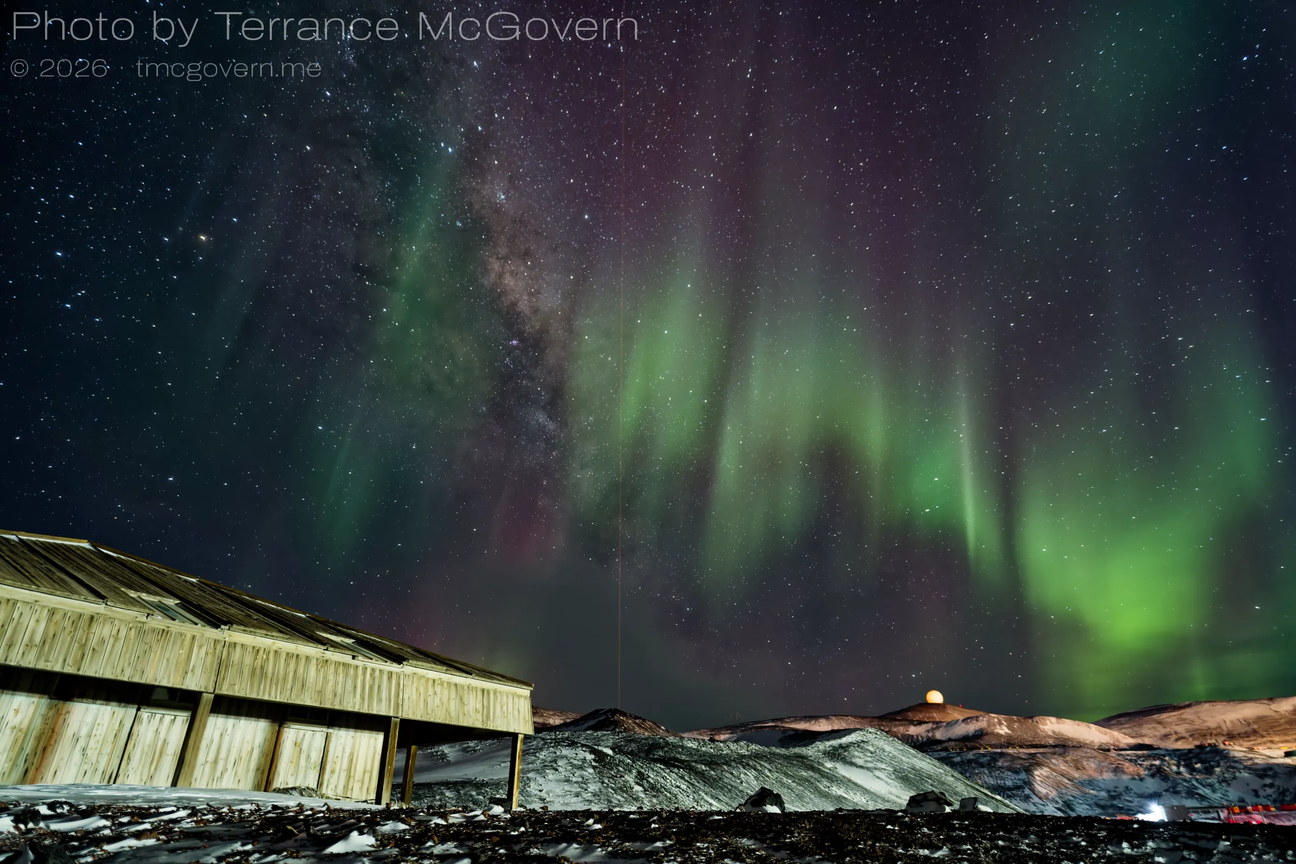 Discovery Hut with hut point ridge, the radome and the laser beam from the lidar lab in the background