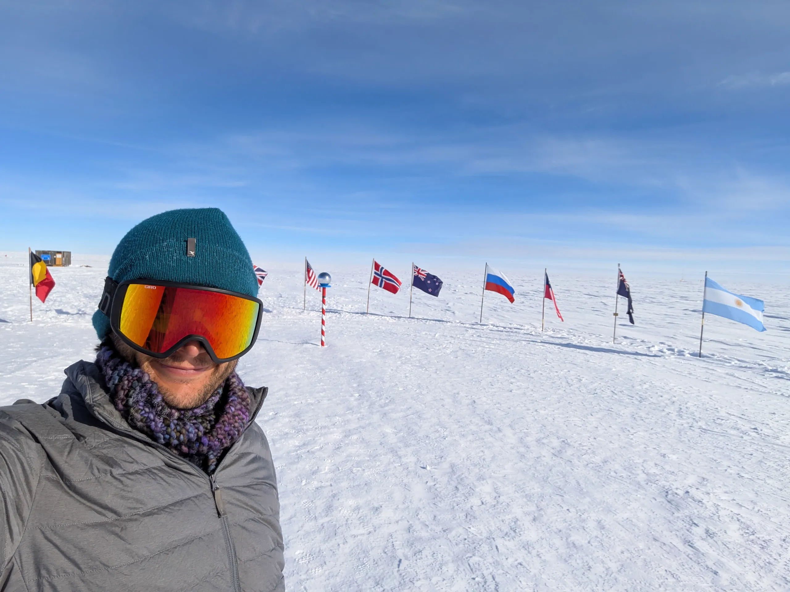 The pole sits on a massive ice shelf that slowly moves across the continent. As such, the station (and everything on the surfaces) moves away from the true pole. The geographic pole marker and sign are adjusted back to true 90°S once a year. The ceremonial pole - this picture - is kept in front of the station. The flags are the original signatories of the Antarctic Treaty.